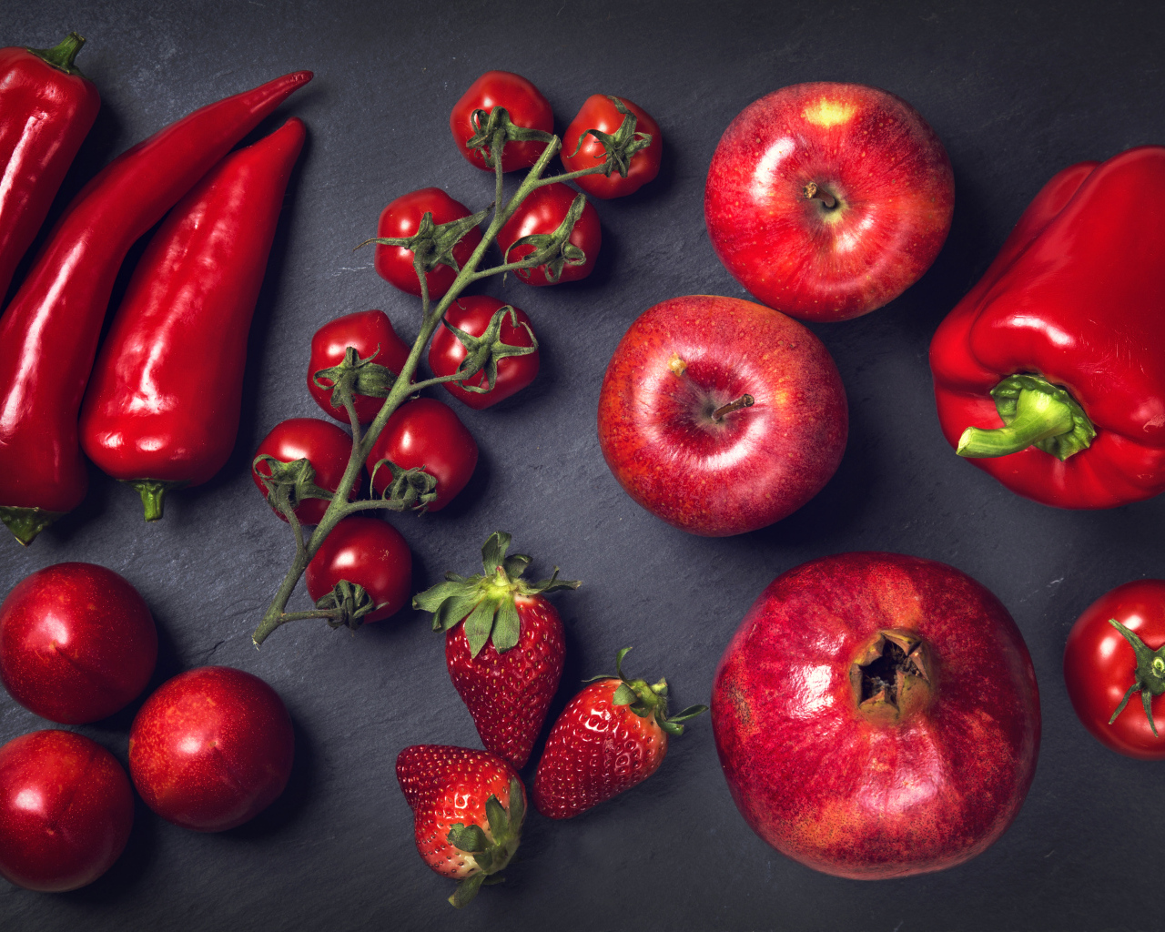 Красные овощи и фрукты на сером столе