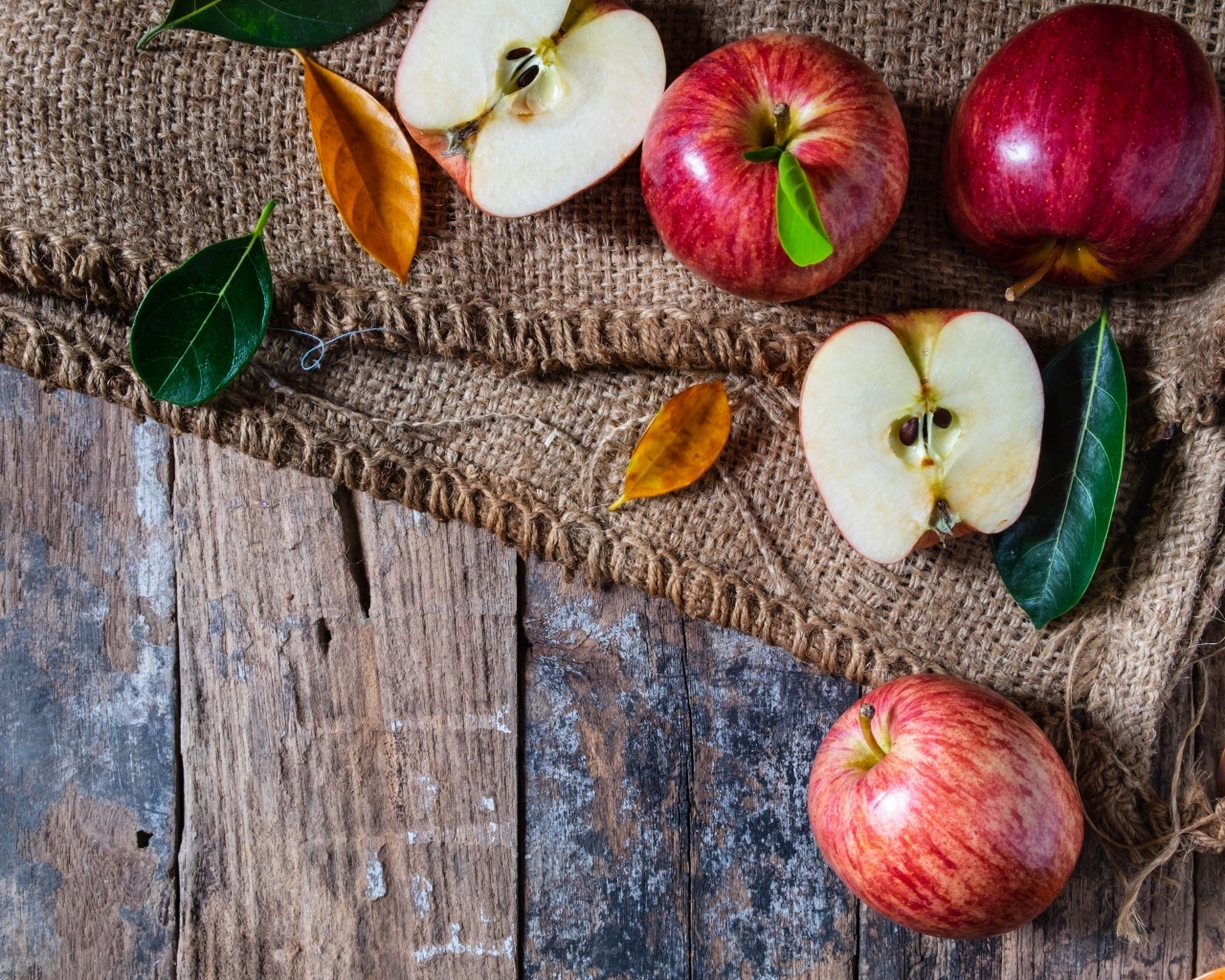 Спелые красные яблоки на столе с мешком
