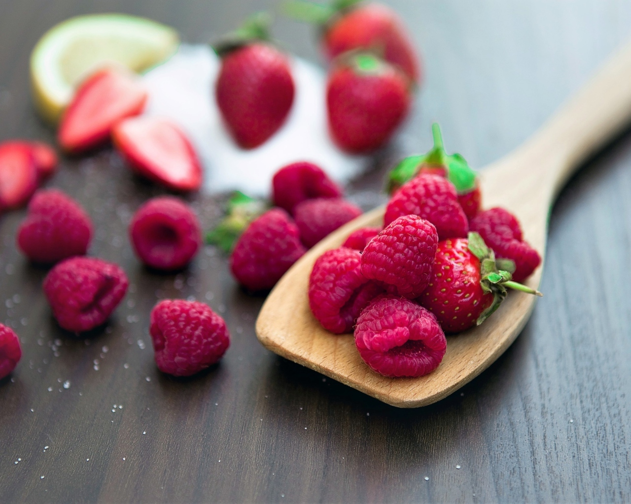 Спелая красная малина с деревянной ложкой на столе