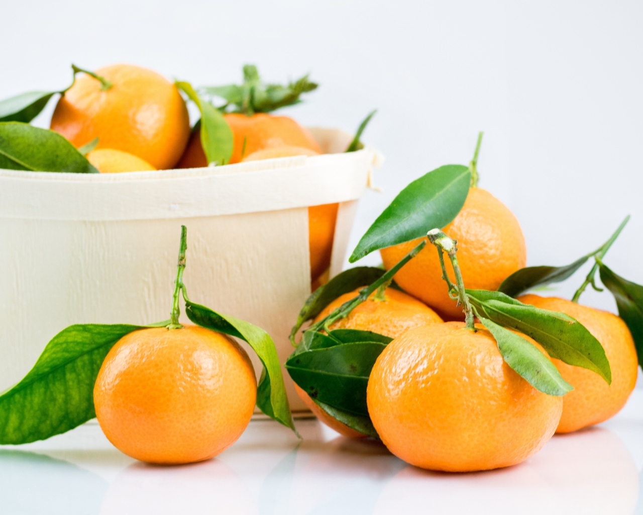 Спелые сладкие мандарины с корзиной на столе