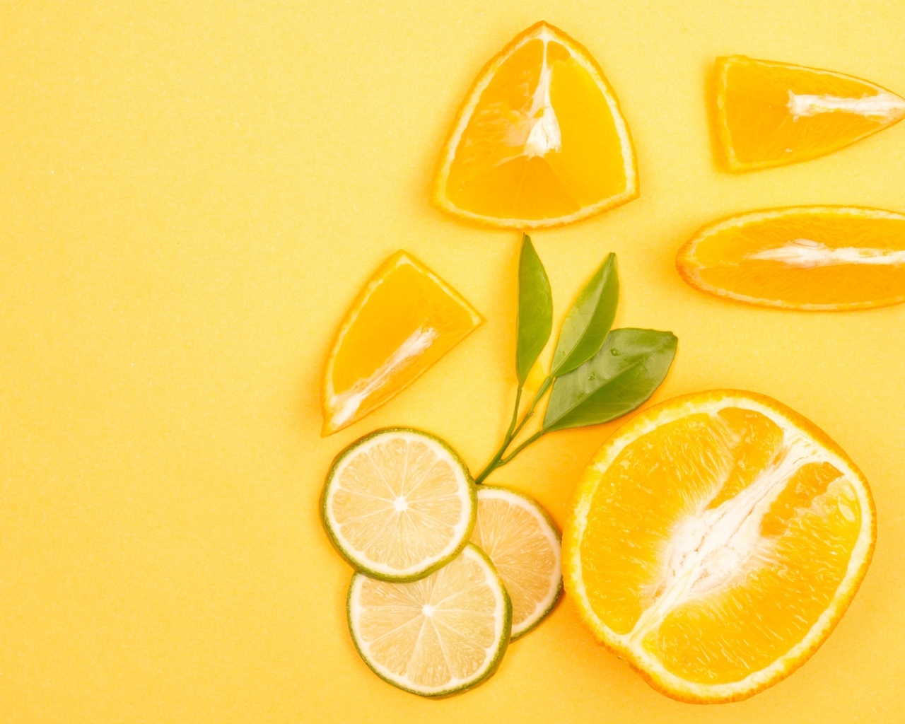 Нарезанные плоды апельсина и лайма на желтом фоне