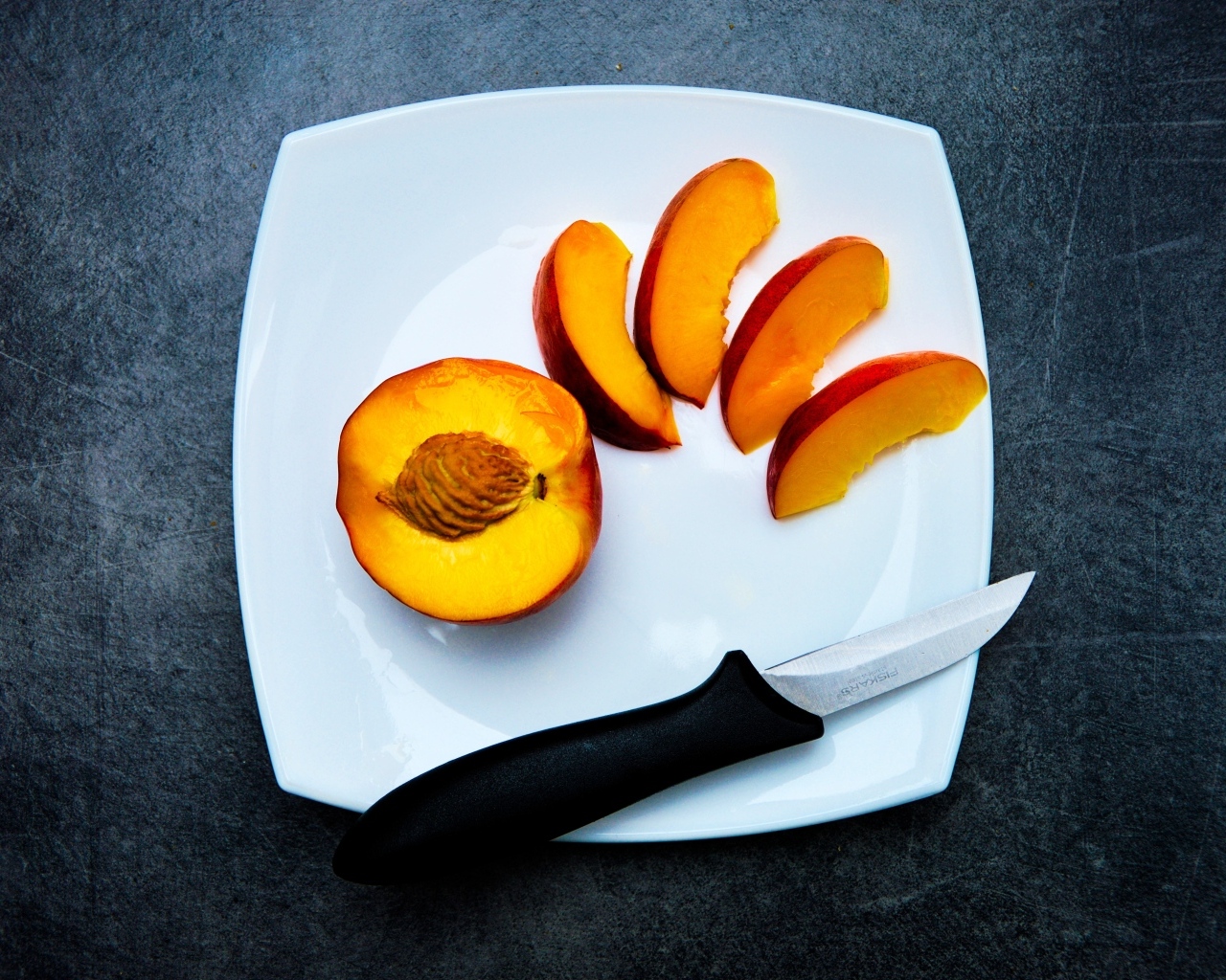 Нарезанный персик на белой тарелке