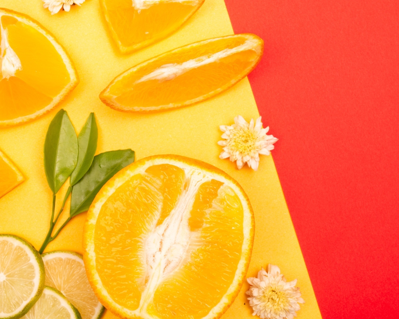 Кусочки апельсина и лайма на разноцветной поверхности 