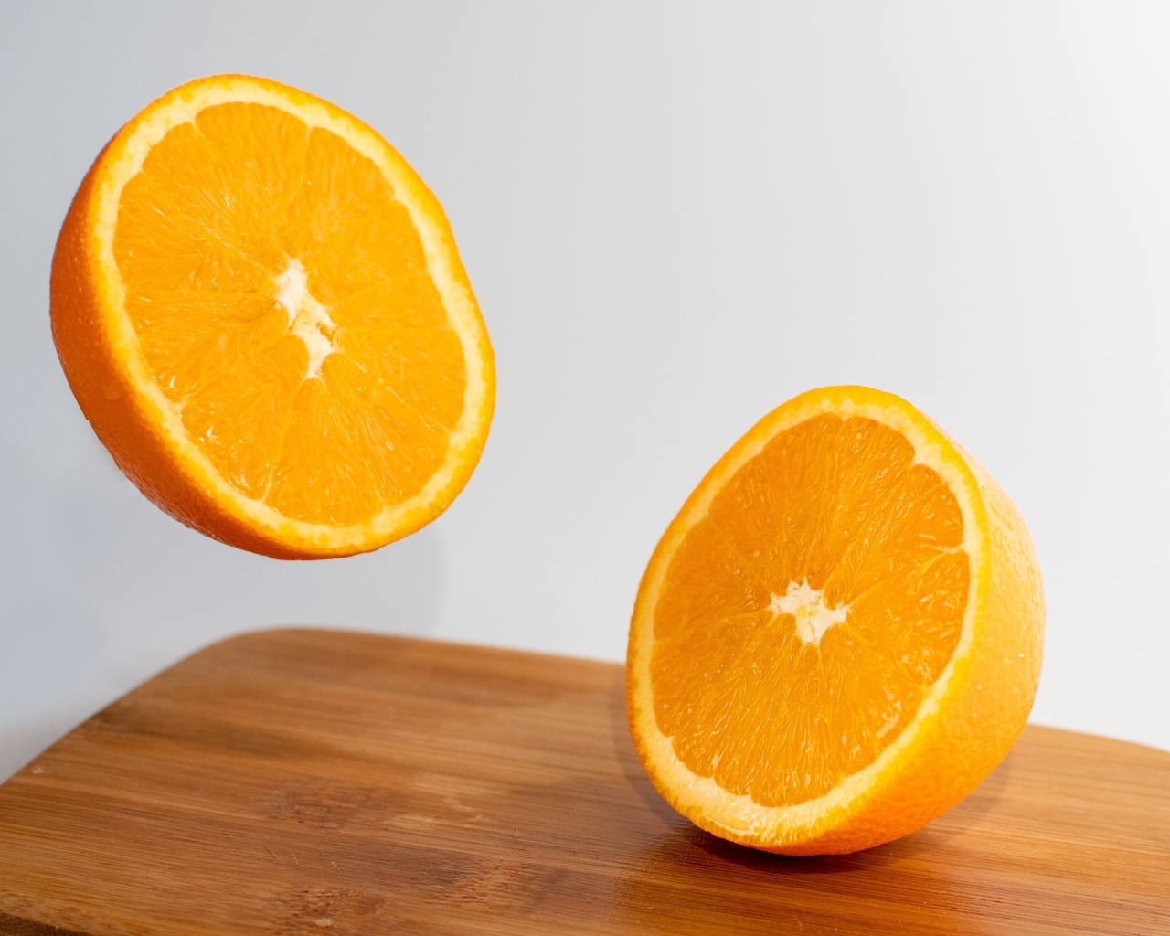 Две половинки апельсина на деревянной доске