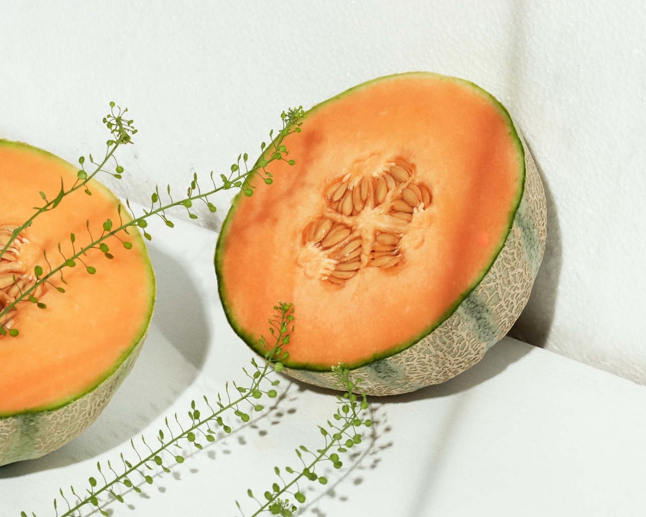 Две половины дыни с травой на белом диване