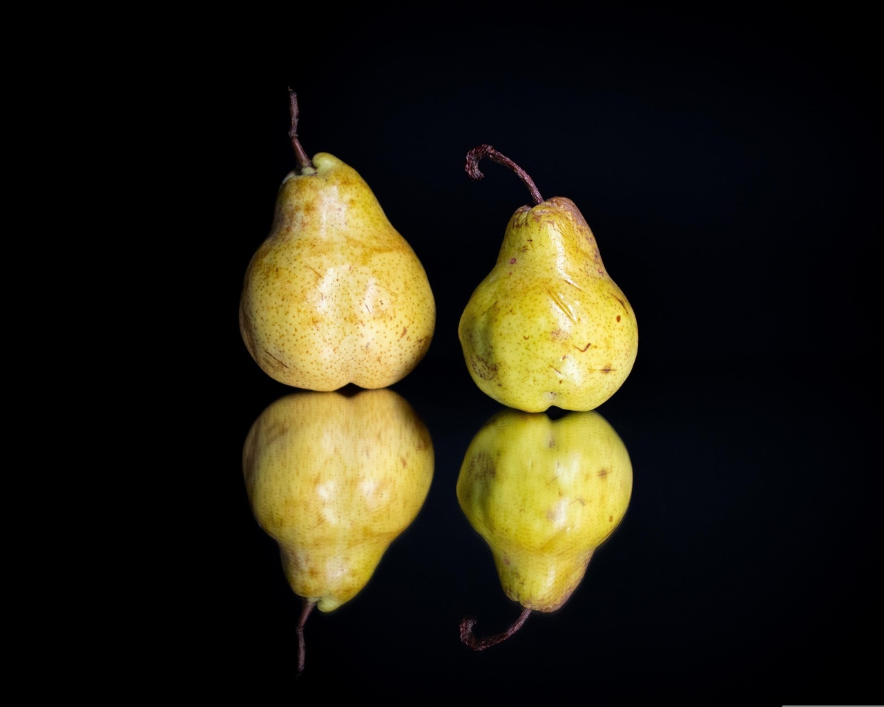 Две груши отражаются в зеркальной поверхности 