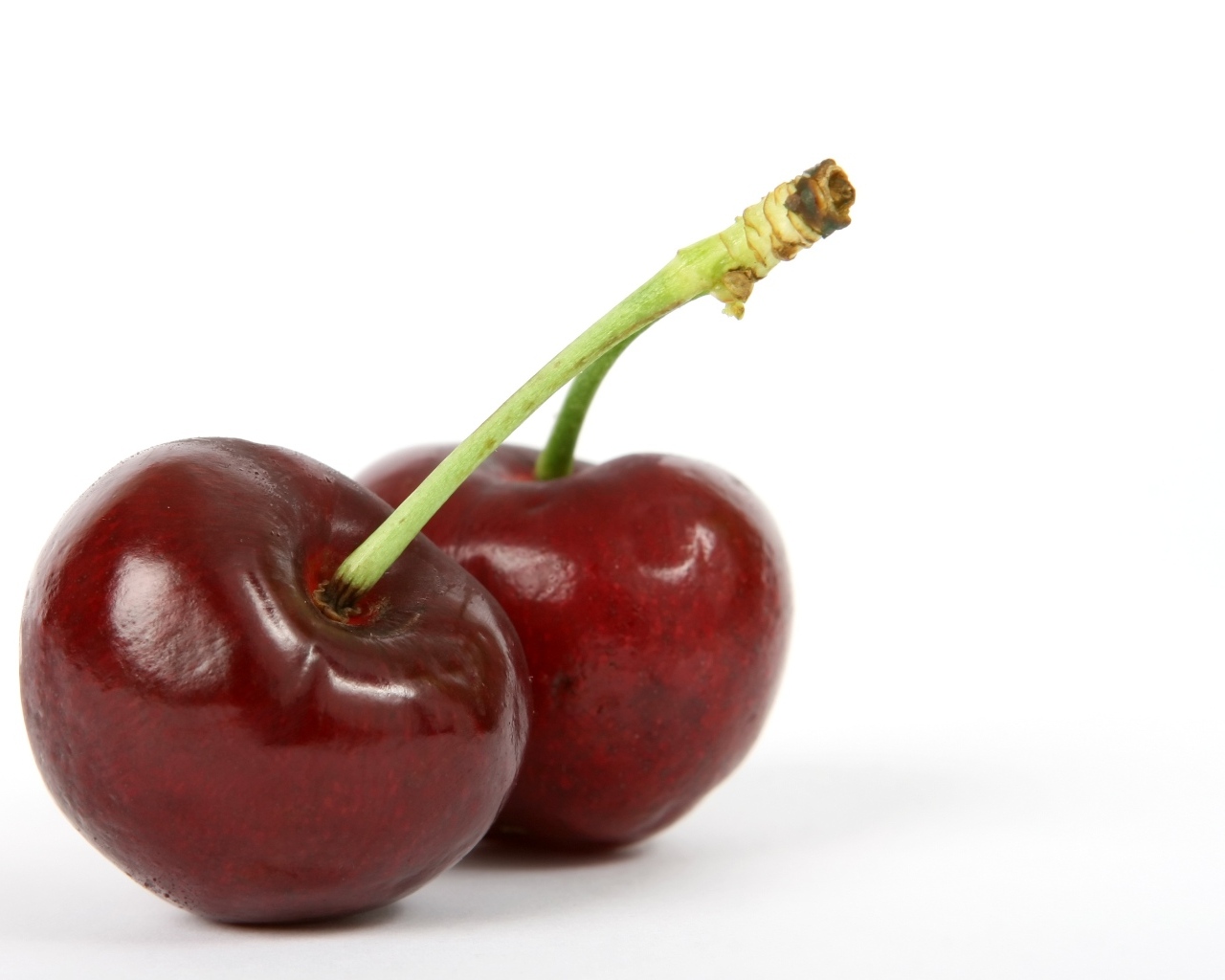 Две красные ягоды черешни на белом фоне