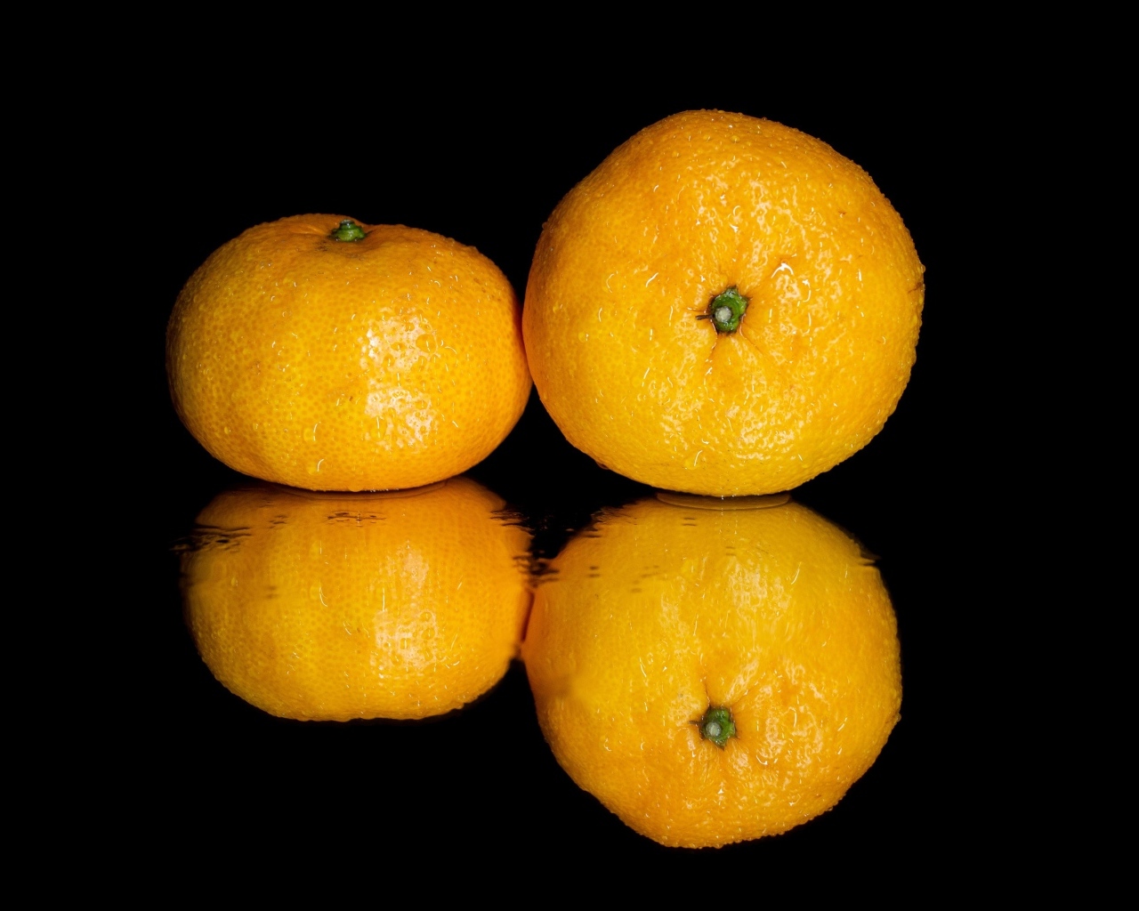 Два мандарина на черной зеркальной поверхности 