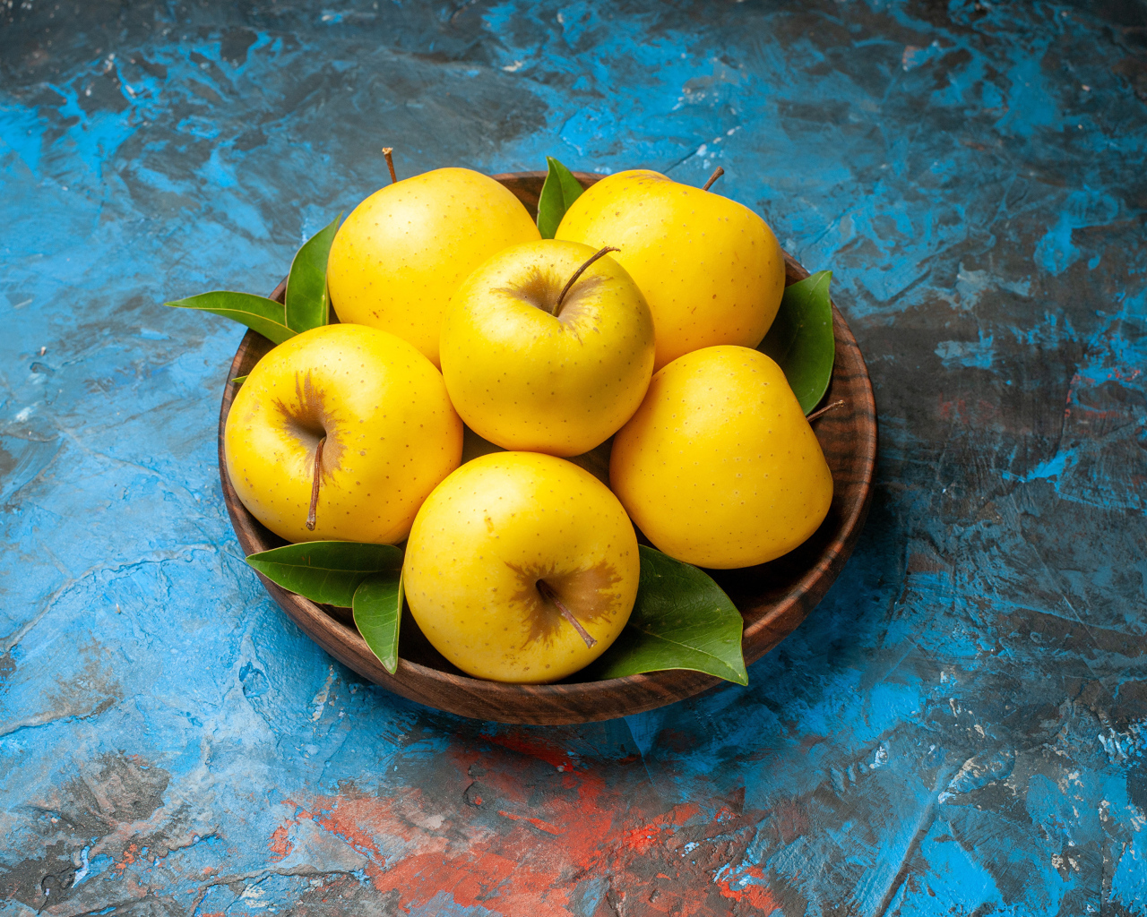 Деревянная тарелка с яблоками на столе