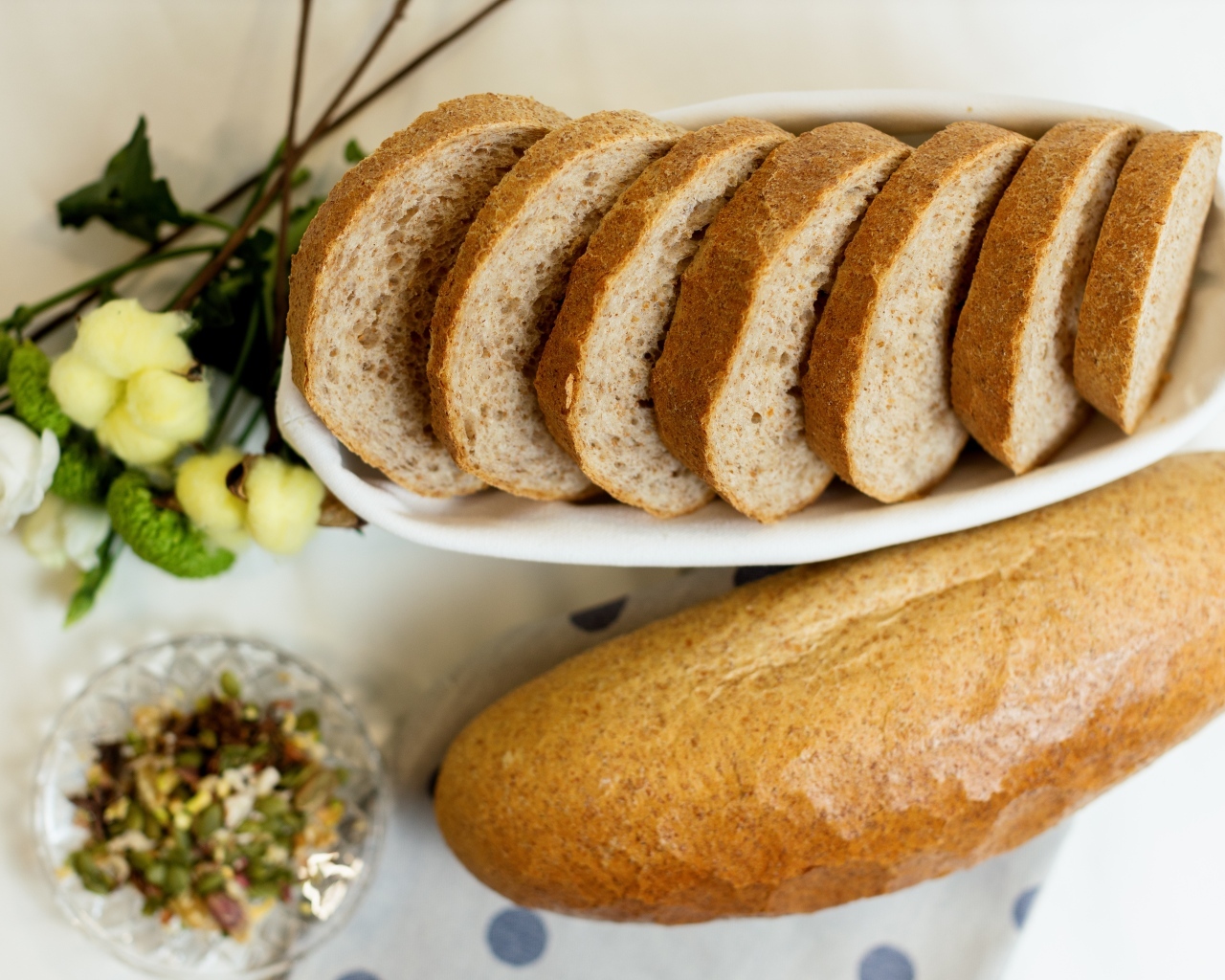 Батон нарезанный на столе с цветами