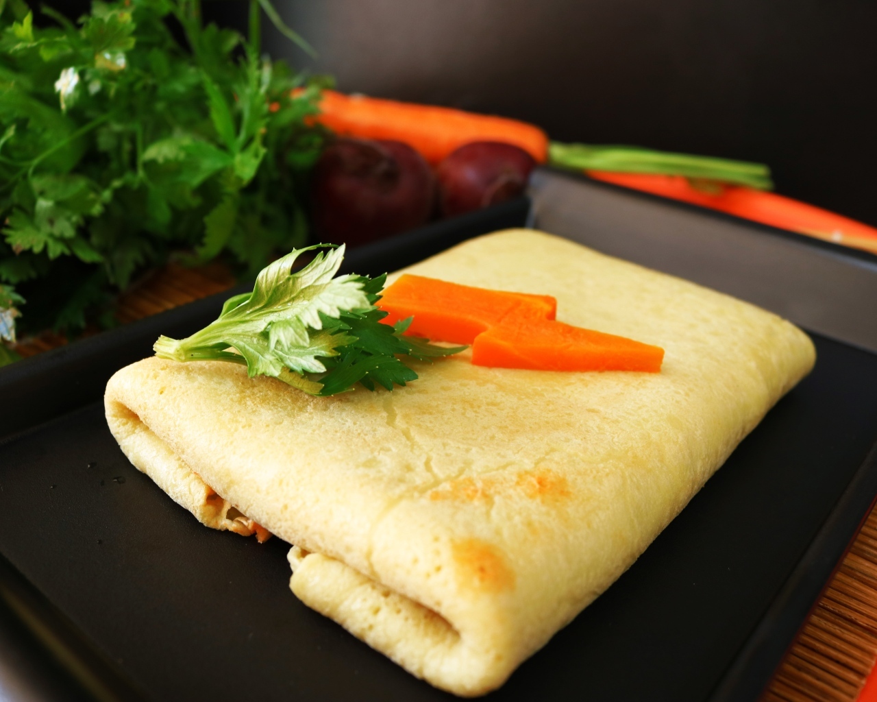 Блинчик на тарелке с морковью и веточками петрушки