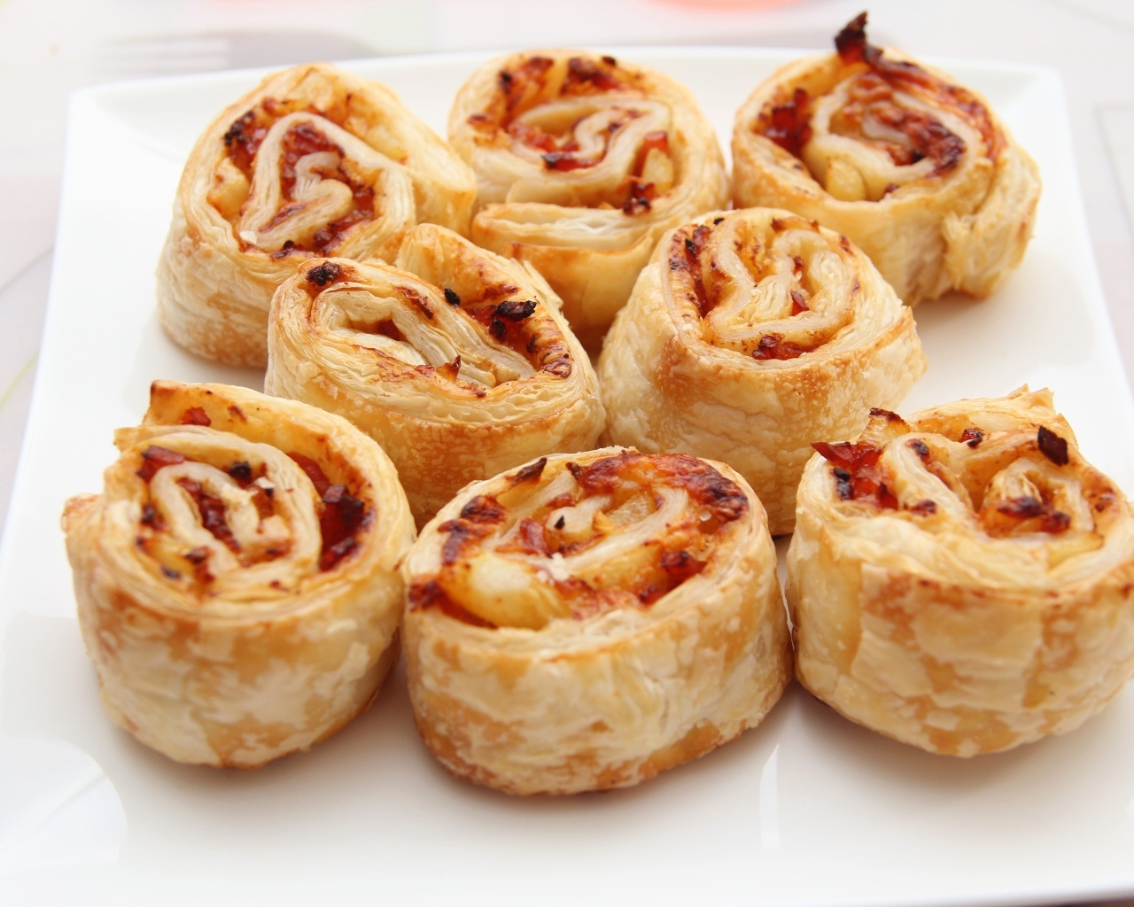 Рулетики из слоеного теста с ветчиной на тарелке