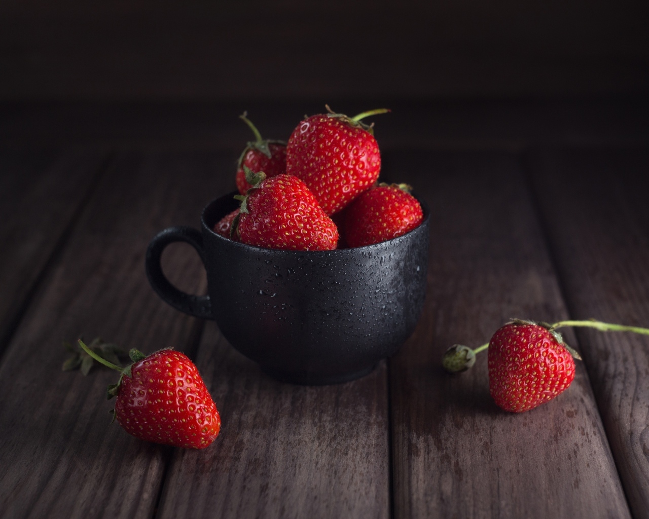 Черная чашка с красными ягодами клубники