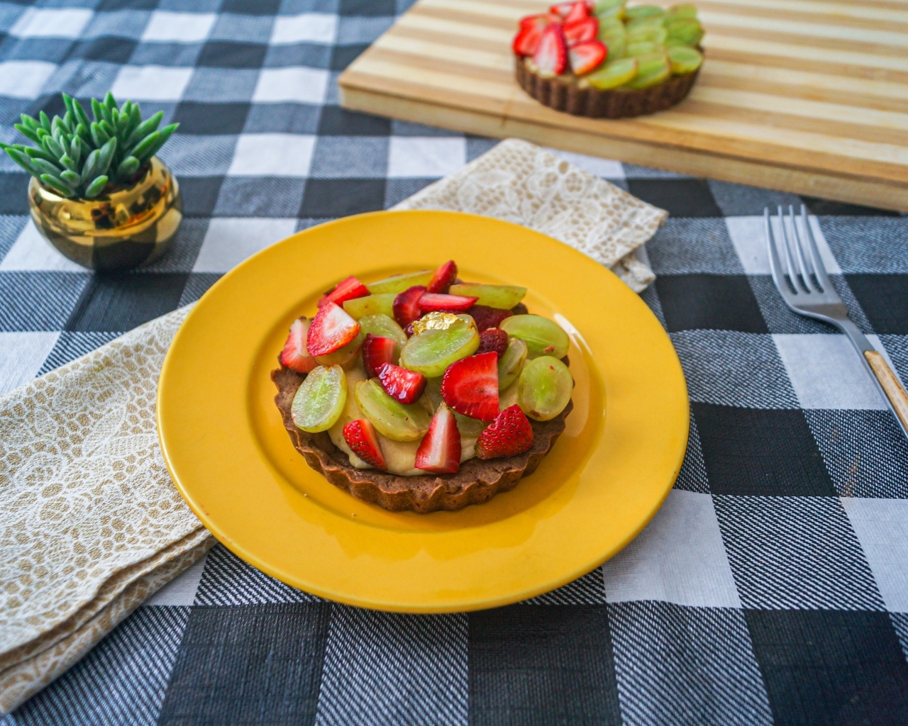 Пирожное с кремом и ягодами клубники и винограда