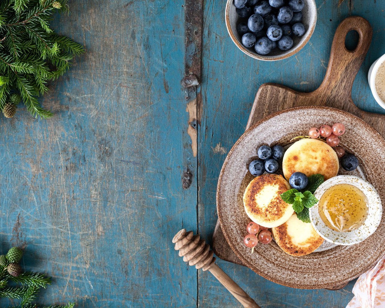 Сырники с ягодами черники на тарелке с медом