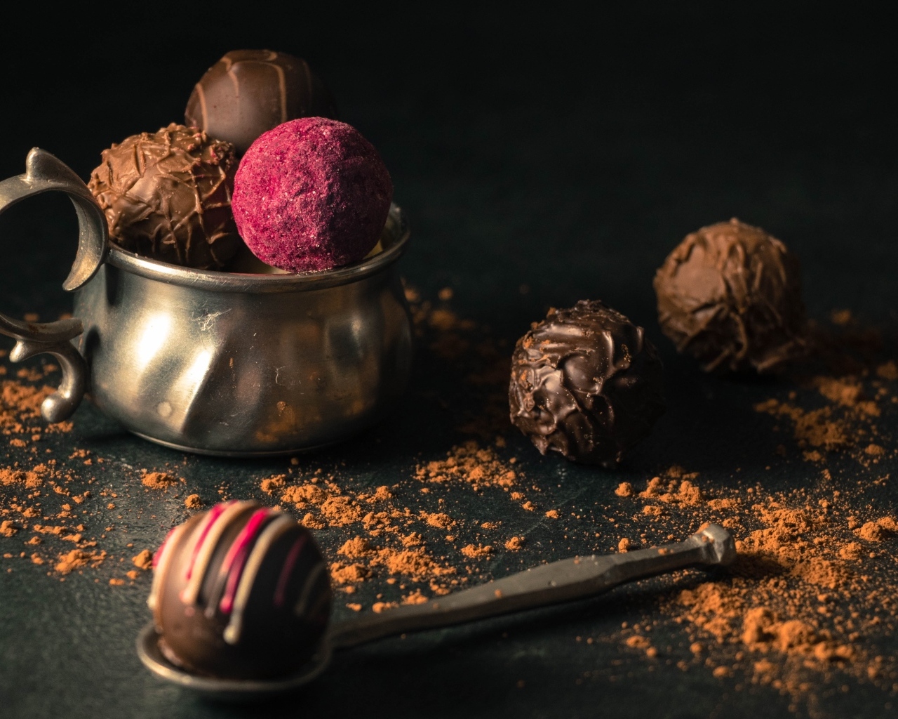 Шоколадные конфеты с железной чашкой на черном фоне