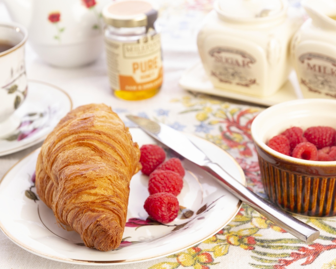 Круассан с ягодами малины на тарелке