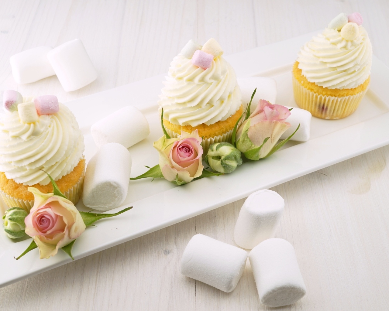 Капкейки с кремом на тарелке с розами и маршмеллоу