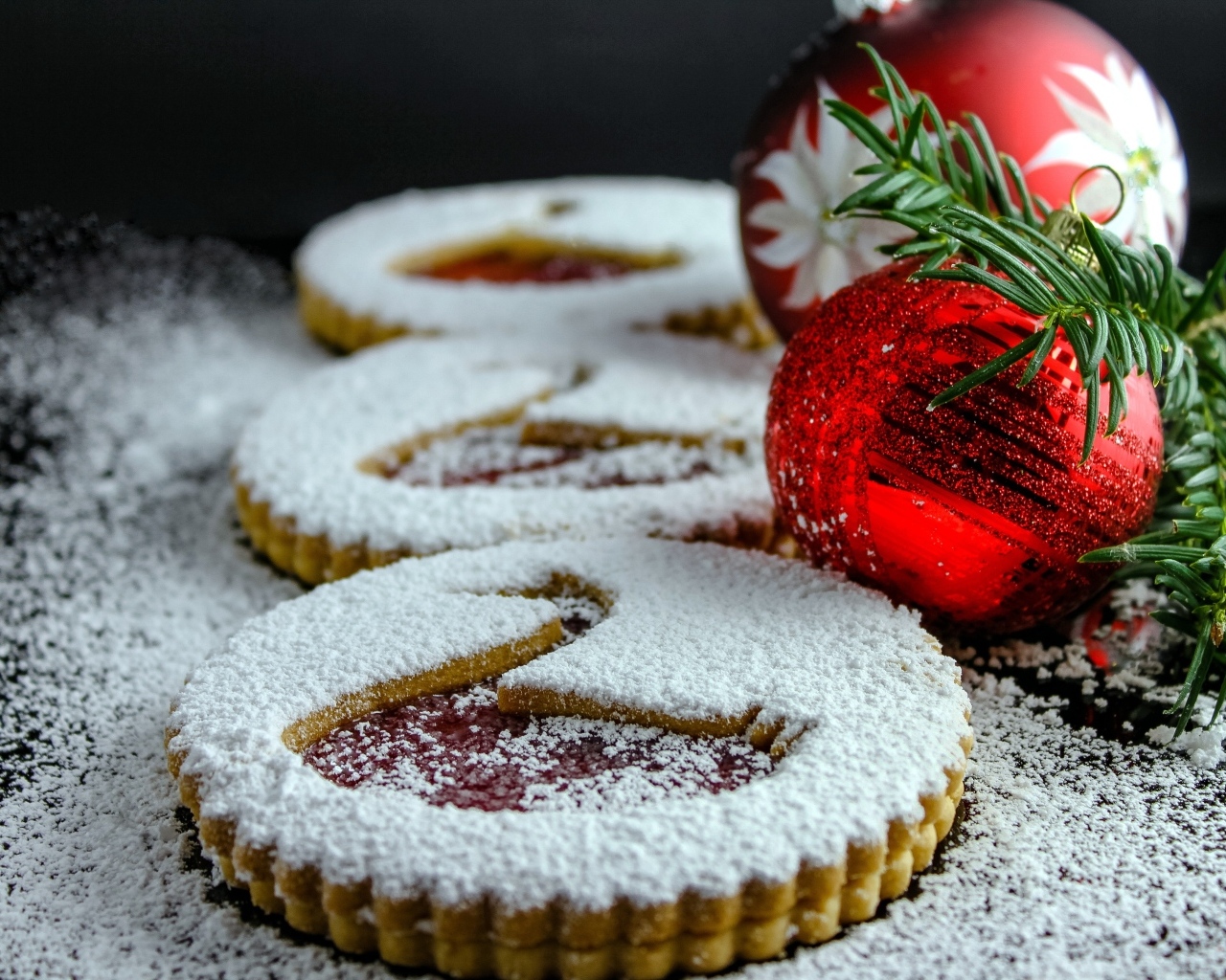 Вкусное сладкое печенье в сахарной пудре на столе с елочными игрушками