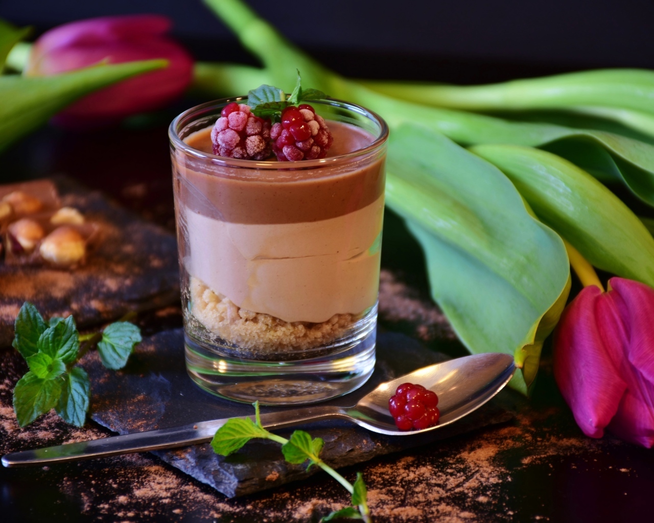 Десерт в стакане на столе с тюльпаном