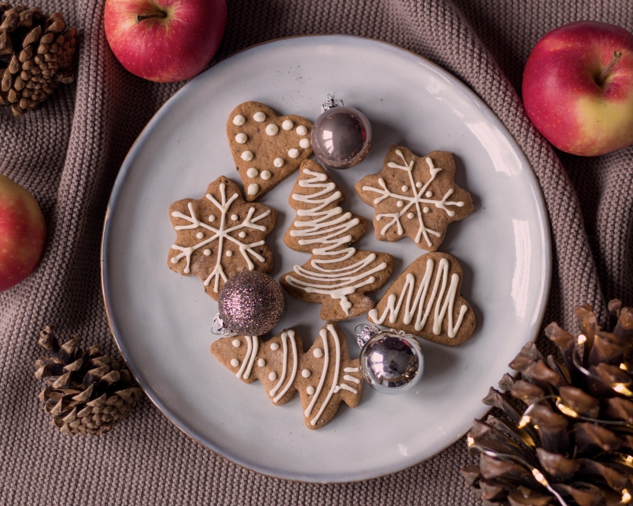Праздничное печенье на столе с яблоками и шишками