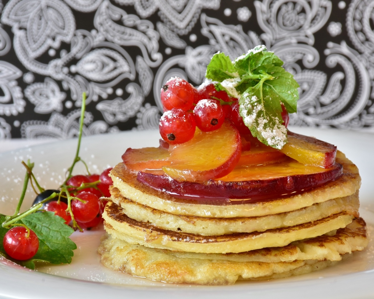 Оладьи на тарелке с ягодами смородины  и сливы