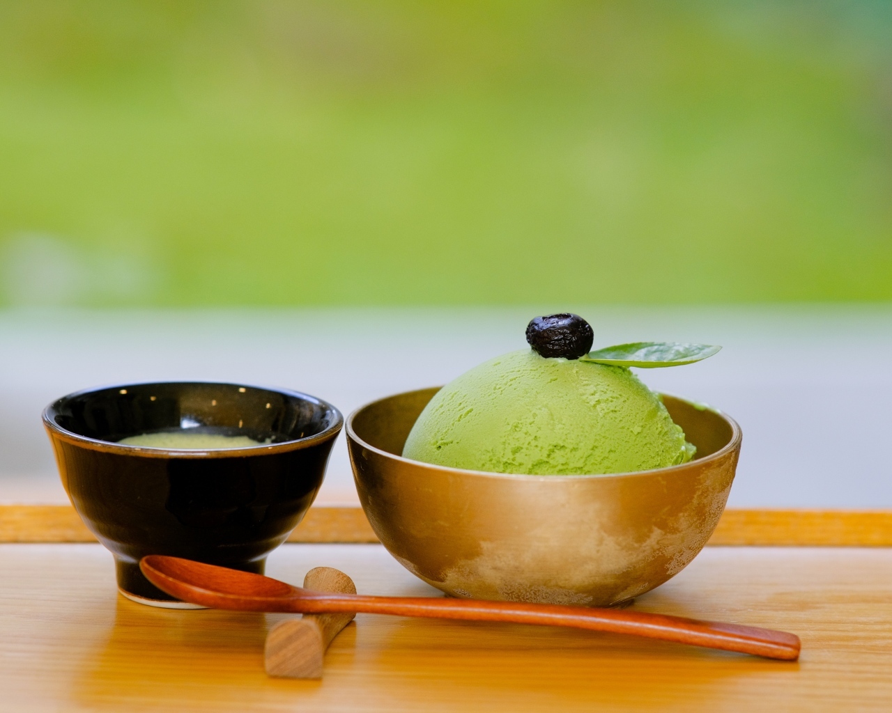 Зеленый шарик мороженого в чашке на столе