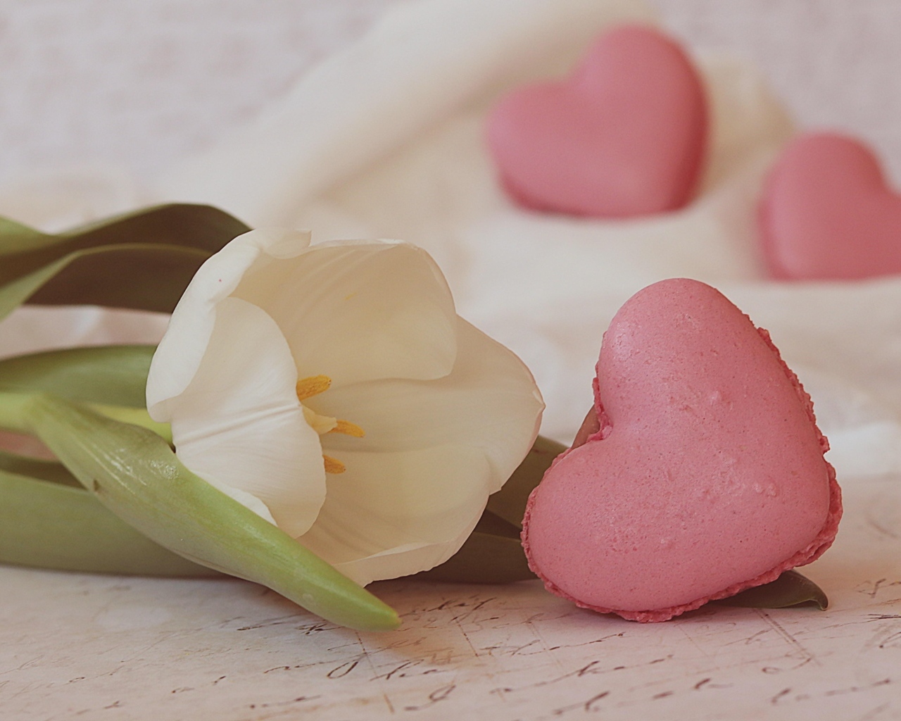 Десерт макарун в форме сердца на столе с тюльпаном