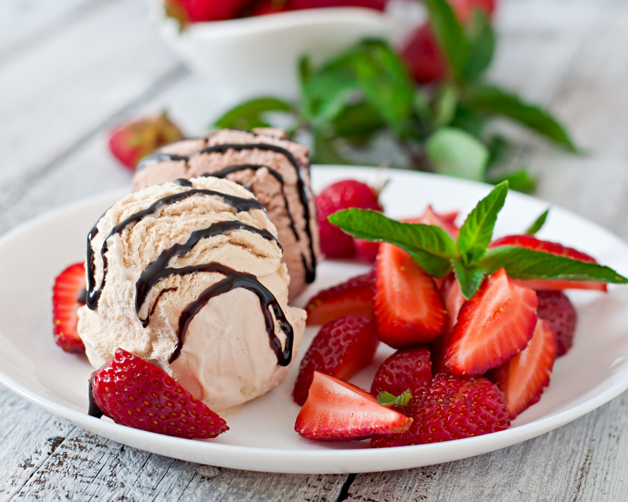 Шарики мороженого на тарелке с кусочками клубники