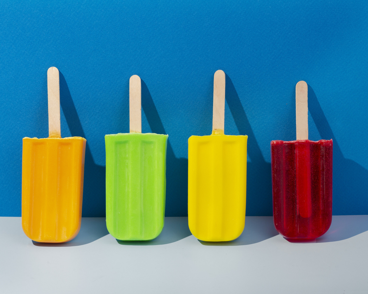 Разноцветное фруктовое мороженое на фоне голубой стены