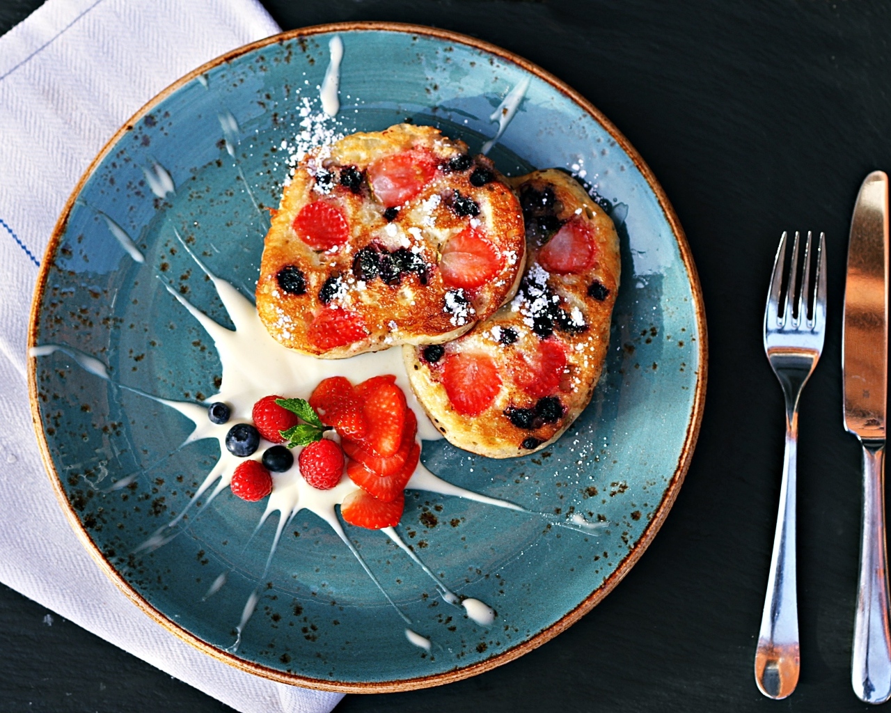 Оладьи на тарелке с ягодами и сметаной