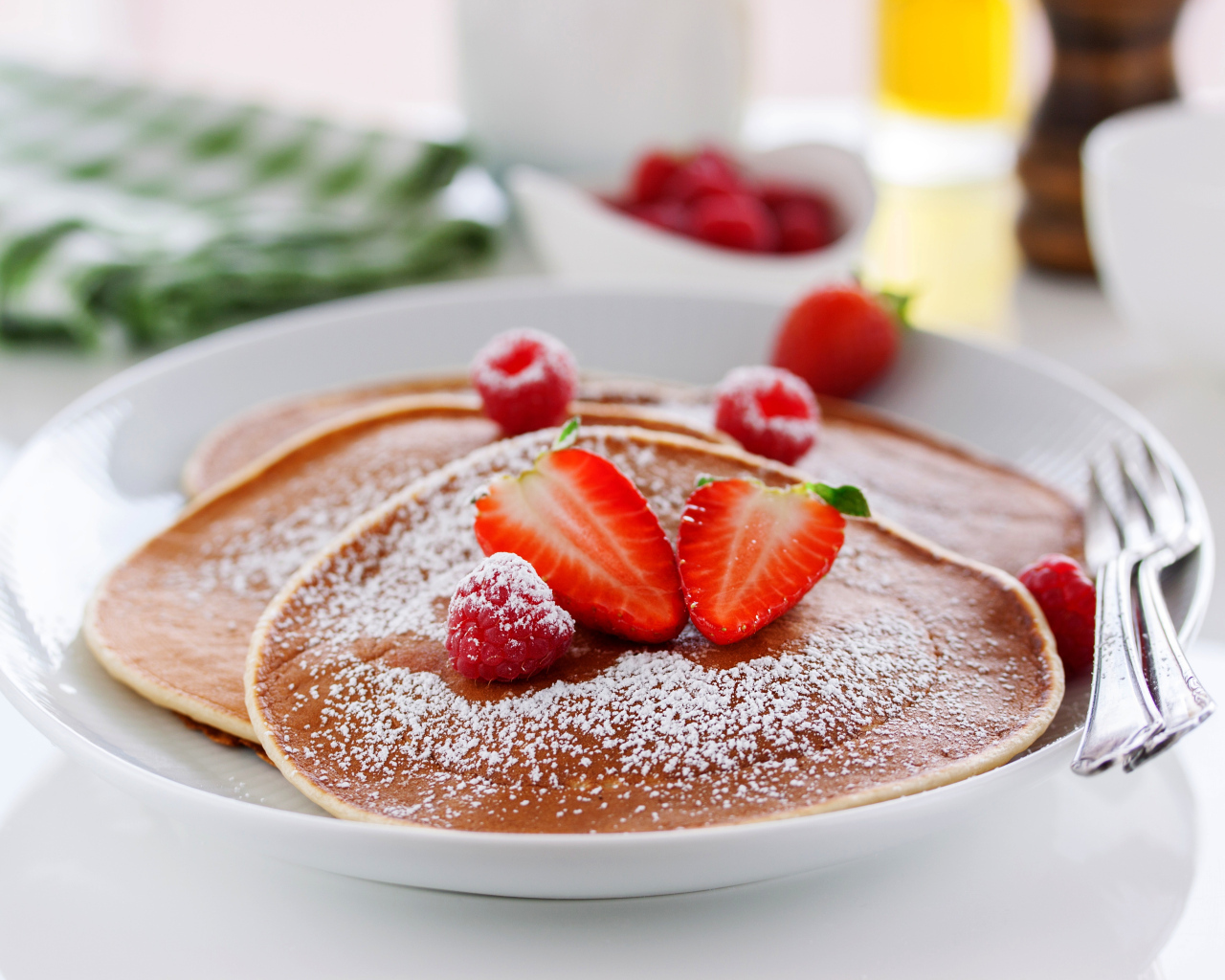 Оладьи на тарелке с сахарной пудрой и ягодами клубники