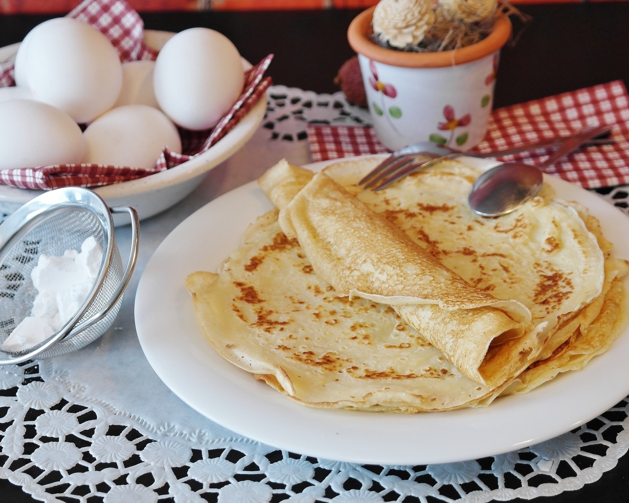 Блинчики на столе  с яйцами и сахарной пудрой