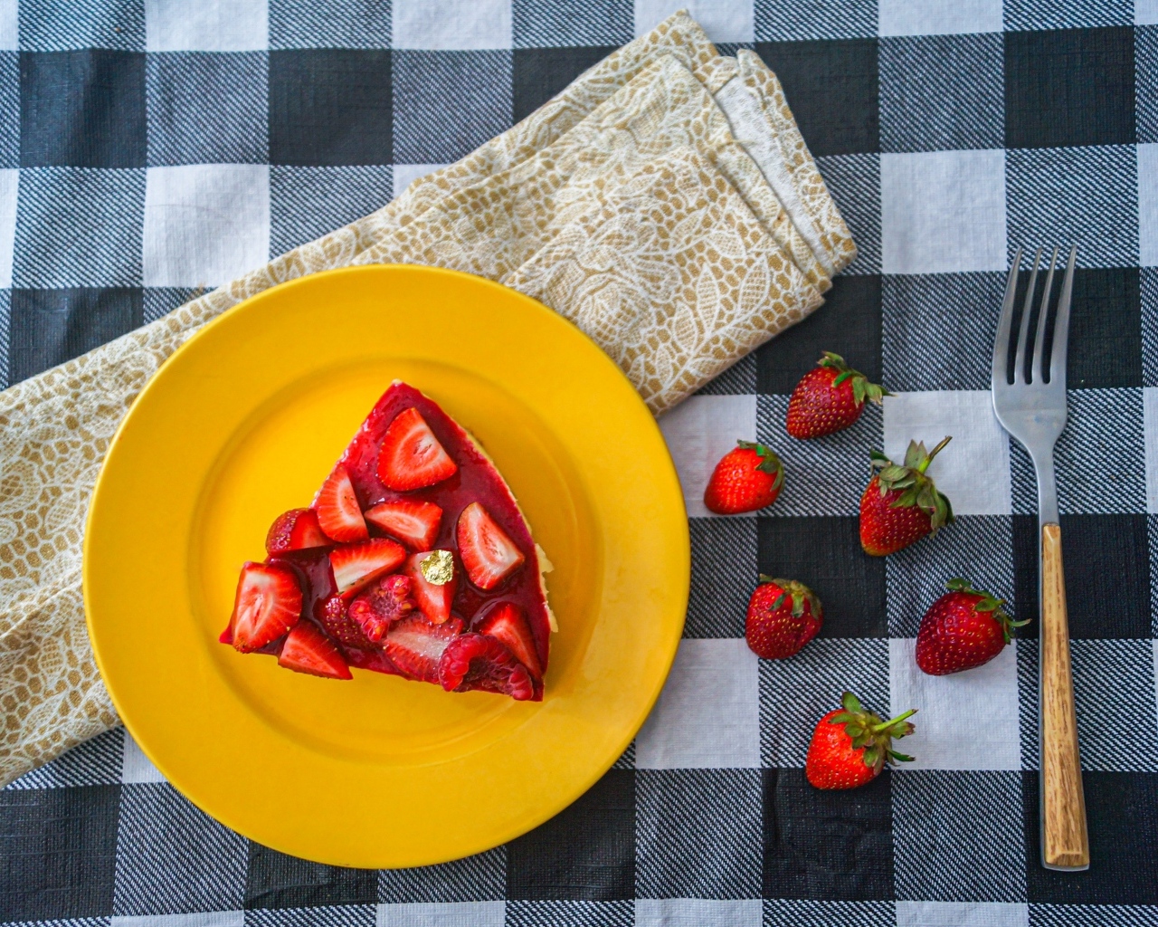 Кусок чизкейка с клубникой на желтой тарелке 