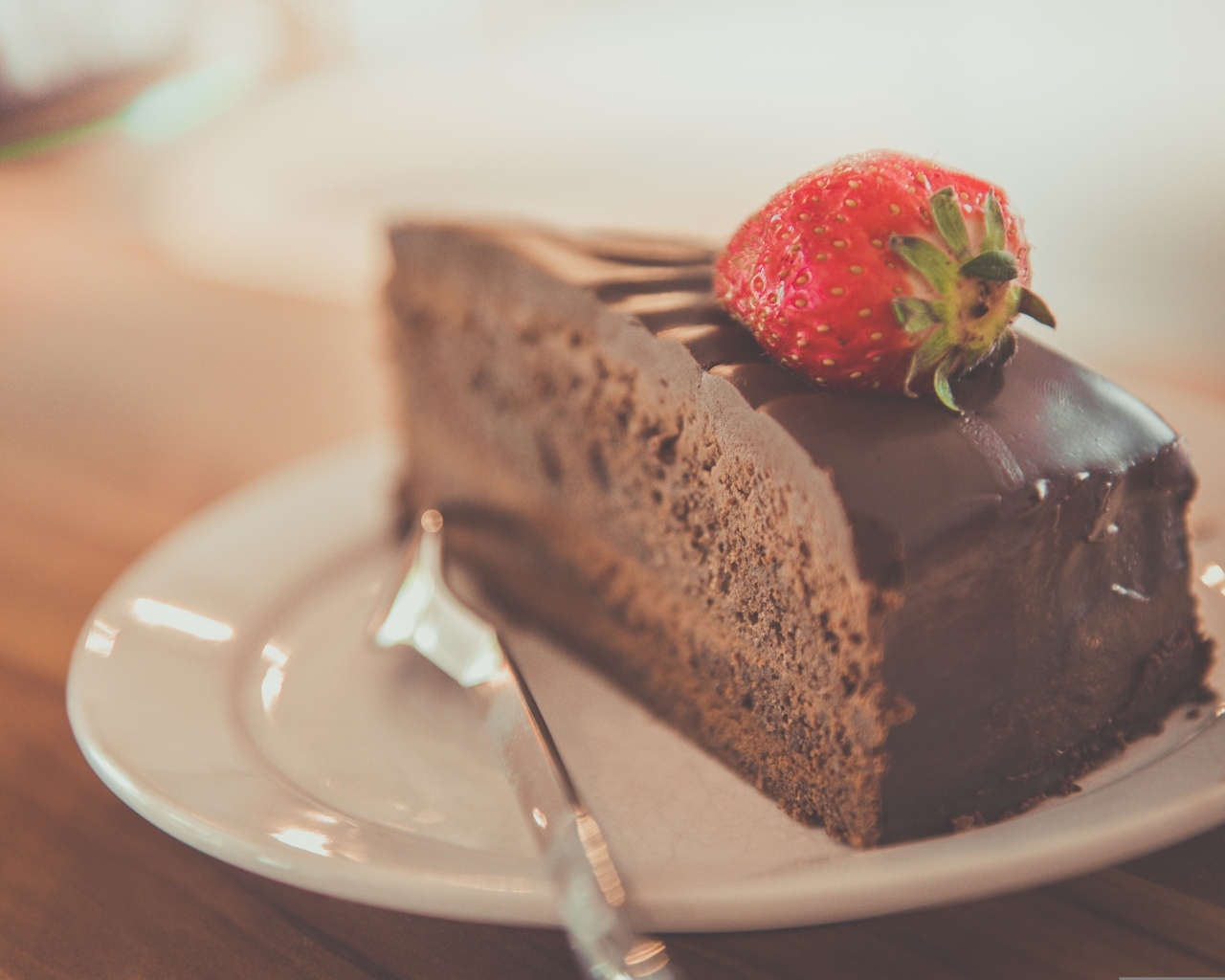 Кусок шоколадного торта с клубникой на тарелке