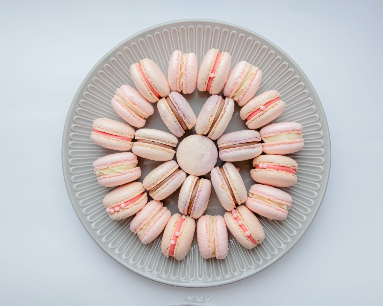 Розовый десерт макарон на большой тарелке