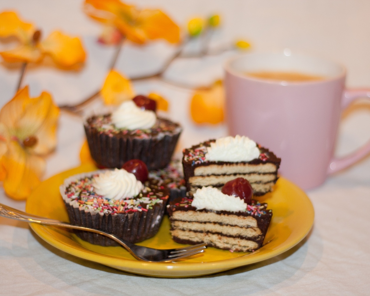 Сладкие вкусные пирожные на столе с чашкой чая и цветами