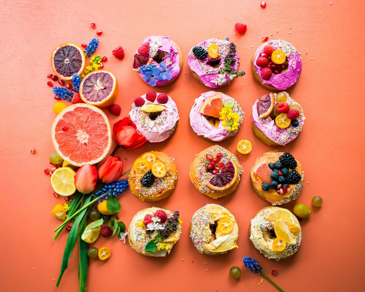 Сладкие пончики на оранжевом фоне с фруктами и цветами