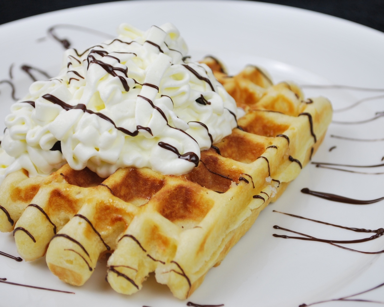 Сладкая вафля со сливками на белой тарелке