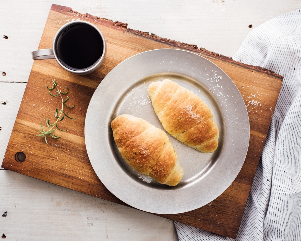 Два круассана на тарелке с чашкой кофе