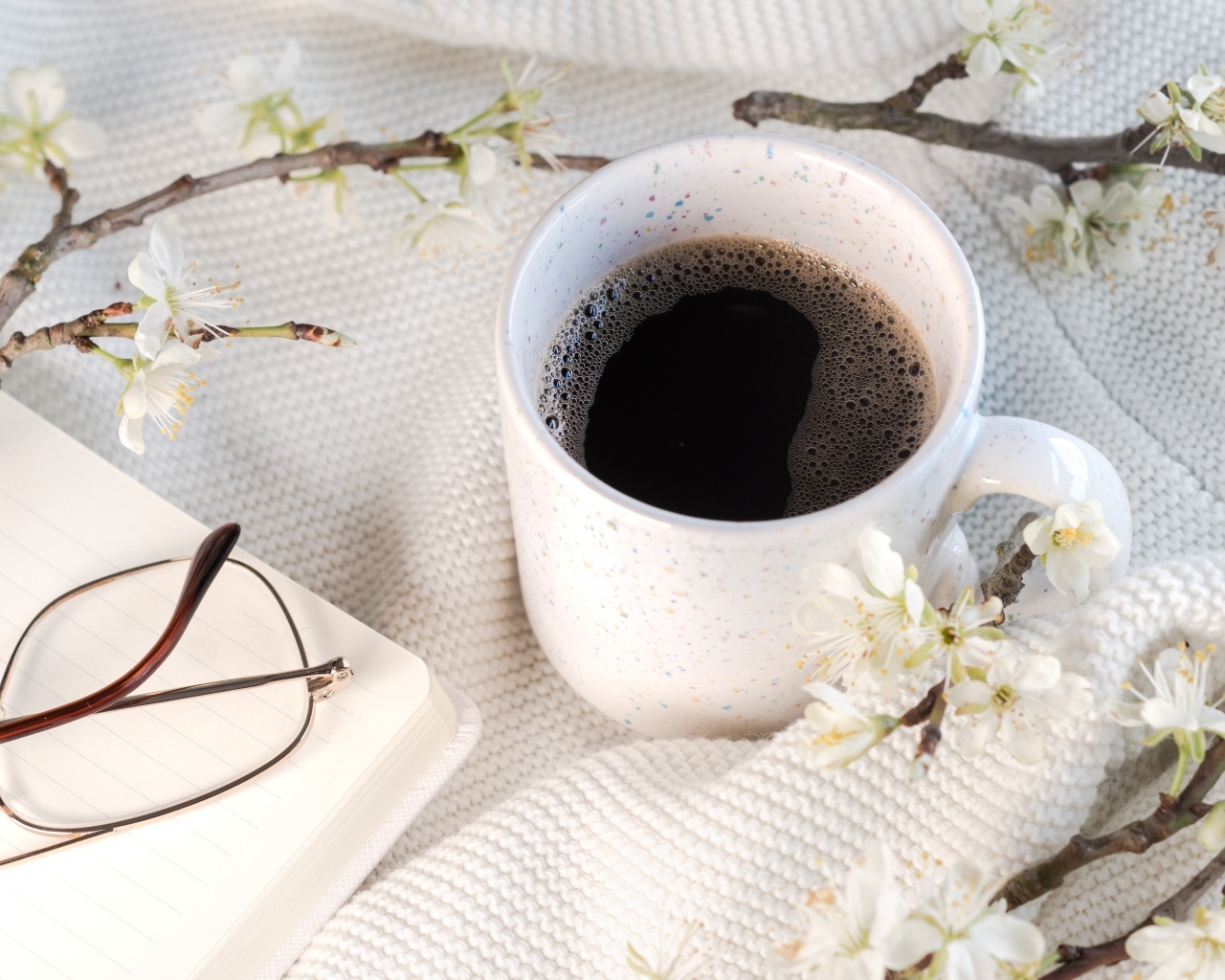 Чашка кофе с цветущей веткой на столе