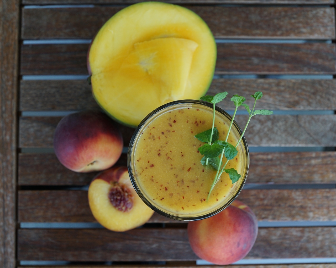 Коктейль с веточкой мяты на столе с фруктами