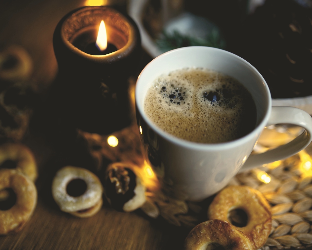 Чашка кофе на столе со свечой и печеньем