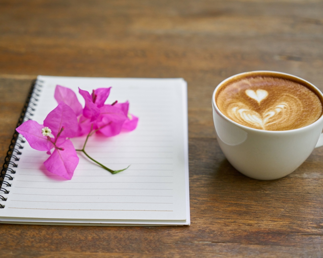 Чашка кофе на столе с блокнотом и цветами