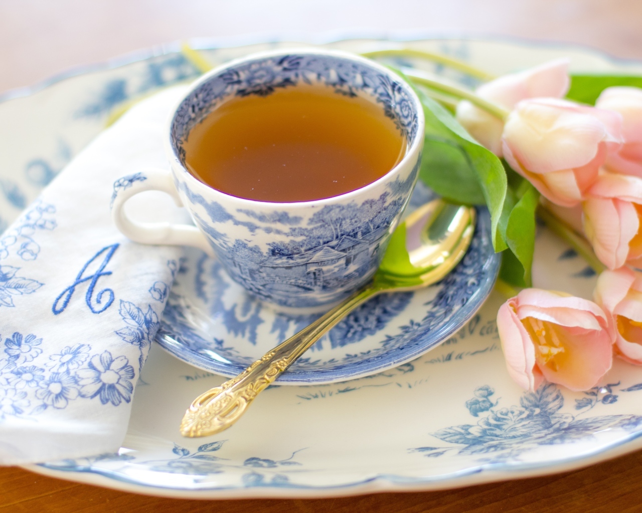 Чашка чая на тарелке с розовыми тюльпанами