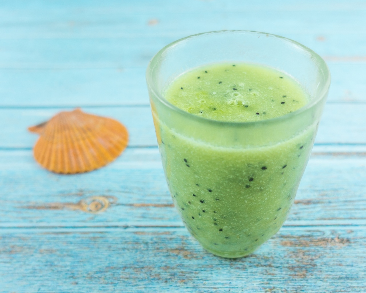 Фруктовый зеленый смузи на голубом столе
