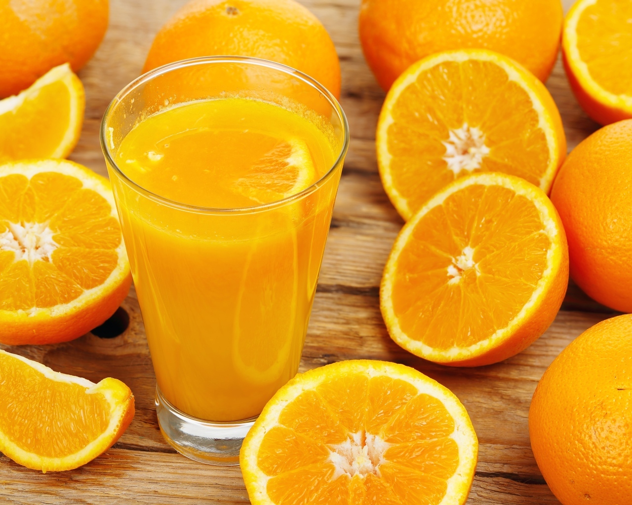 Стакан свежевыжатого сока на столе с половинками апельсина