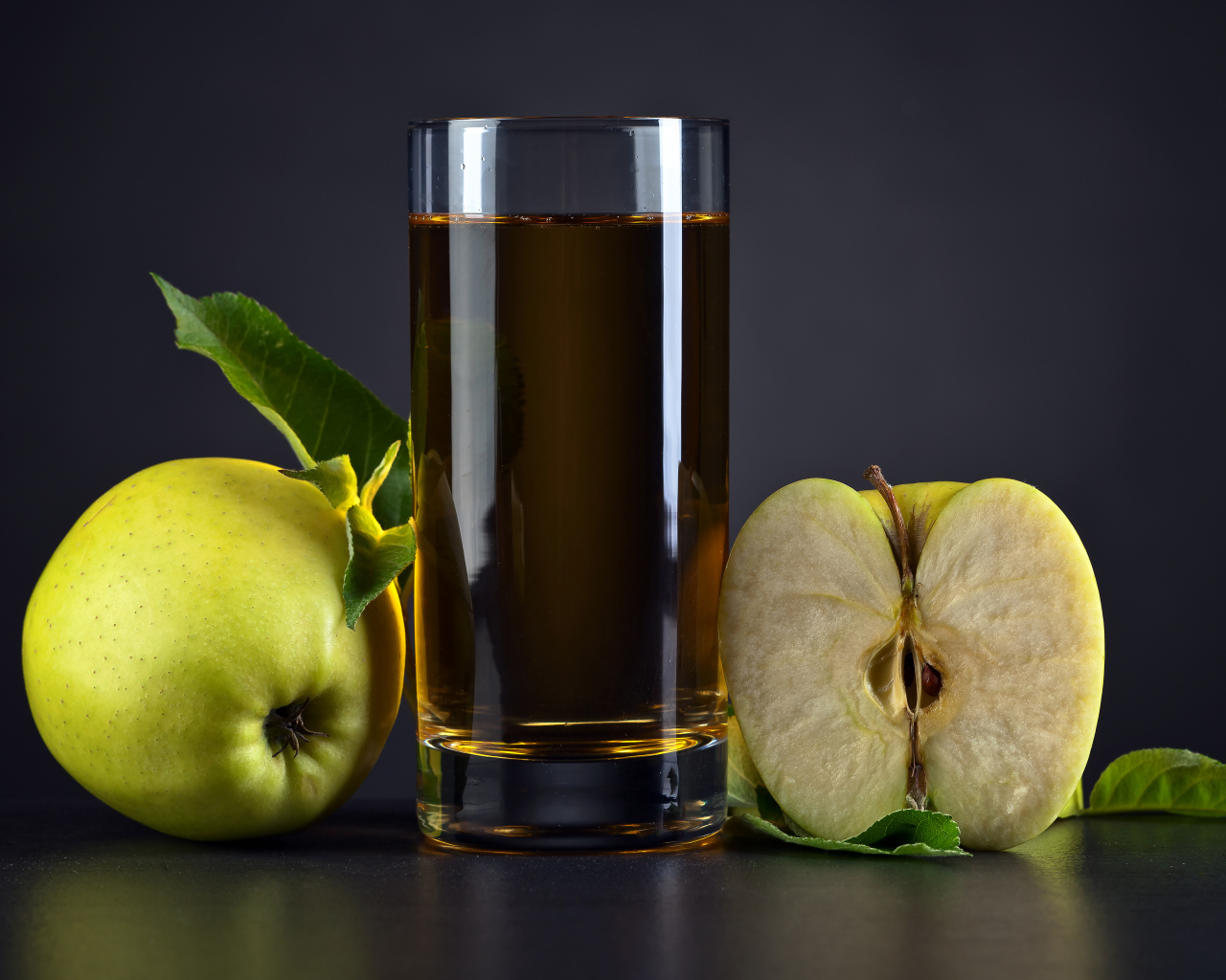 Стакан сока с зелеными яблоками на сером столе