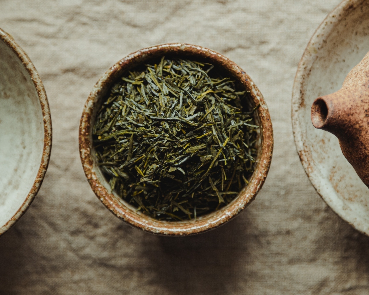 Зеленый чай в пиале на столе с чайником