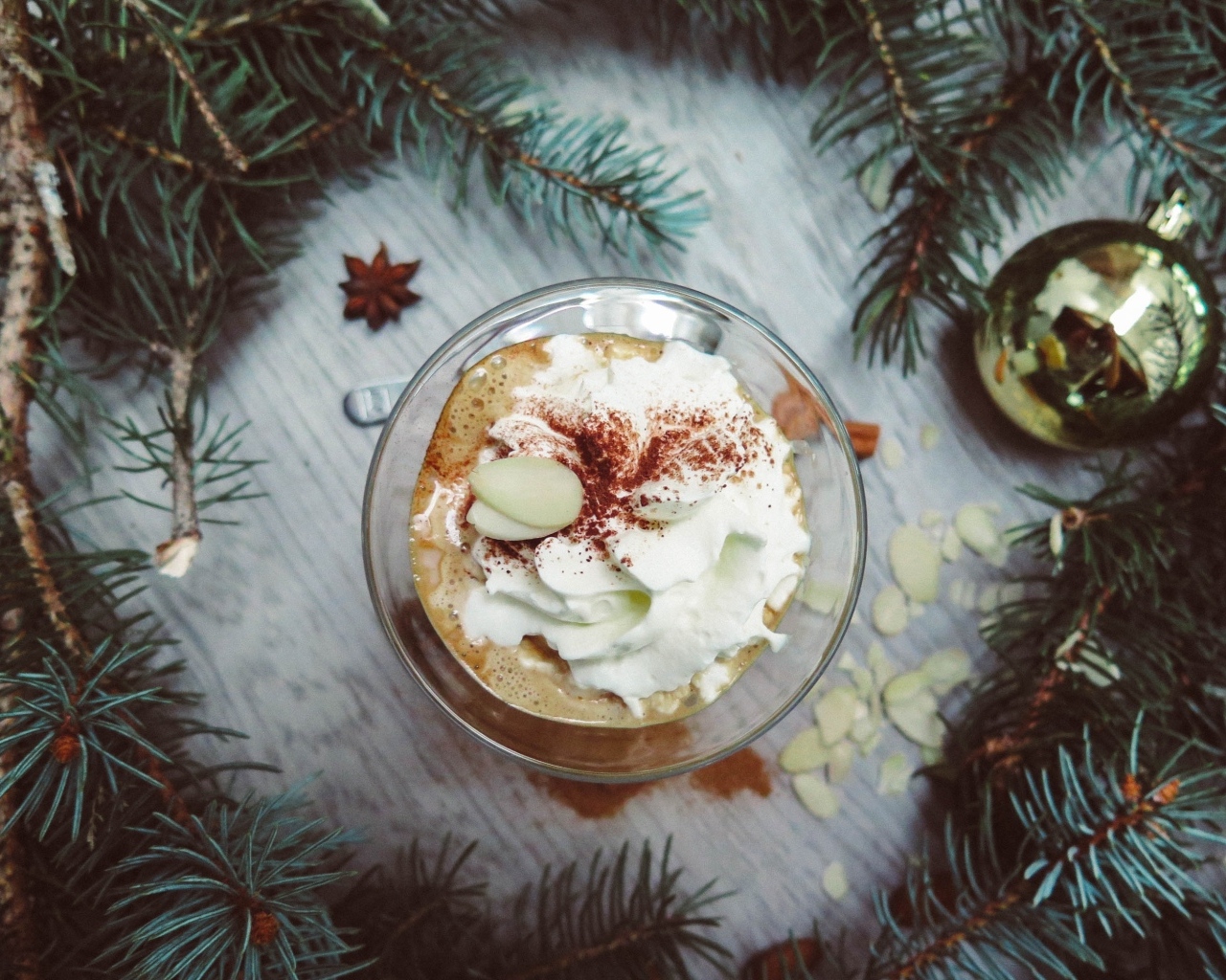 Горячий кофе с взбитыми сливками в чашке на столе с еловыми ветками